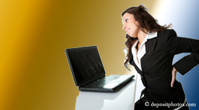 a person Fort Wayne bending over a computer holding her back due to pain